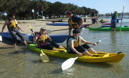 Group of four people in kayaks on beach shore